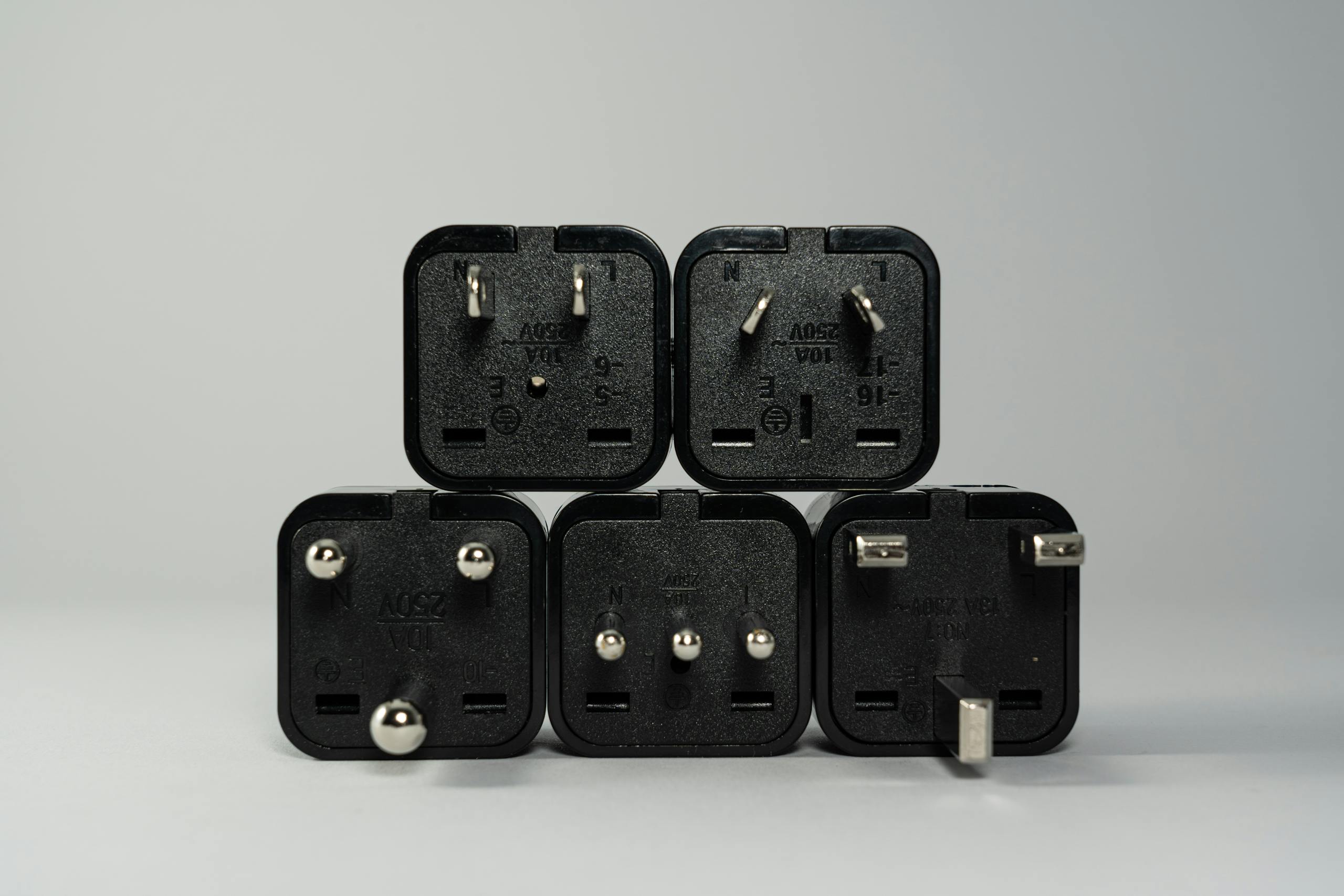 A collection of various black international power plug adapters for global electronics use.
