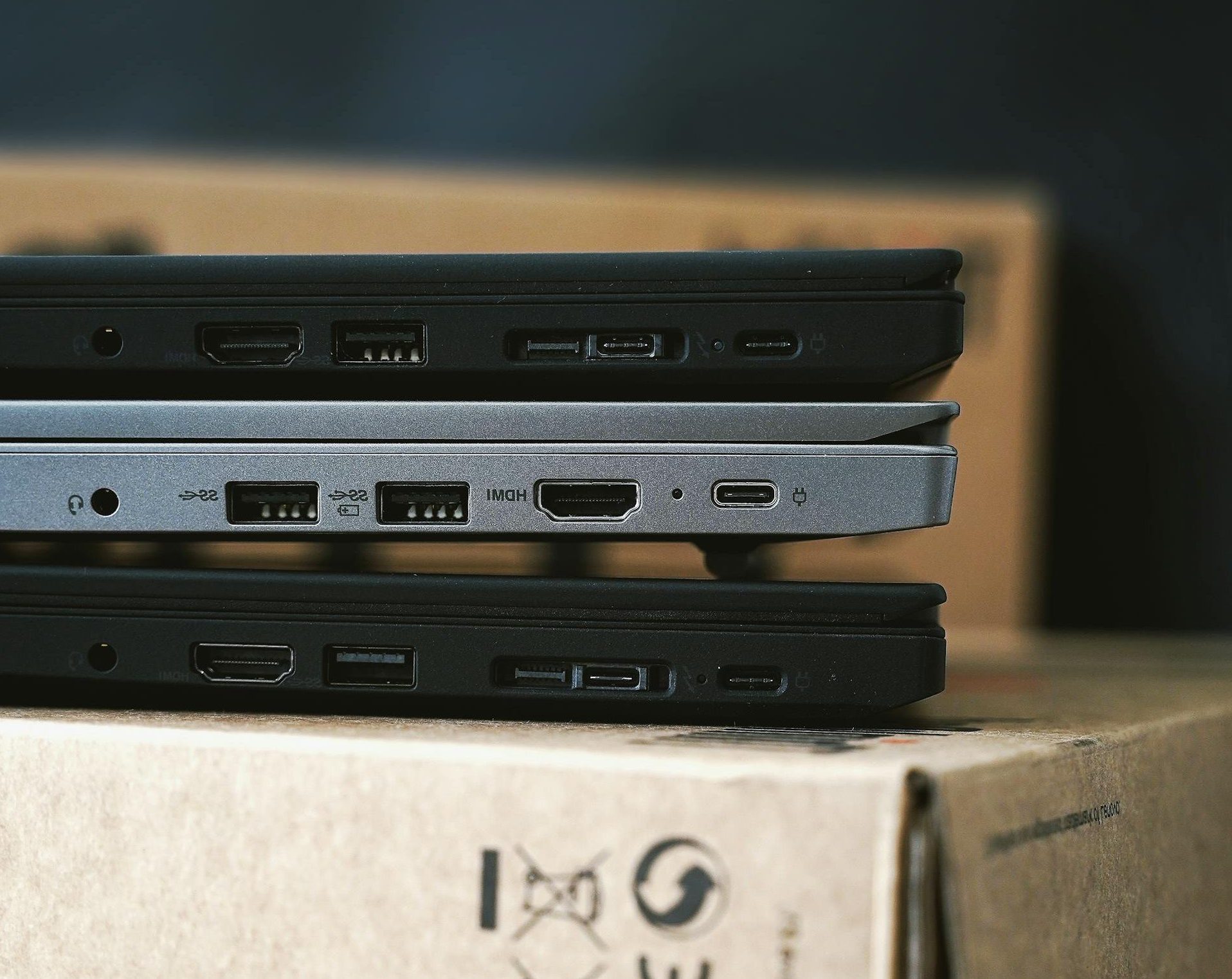 Close-up of stacked modern laptops on cardboard boxes emphasizing portable technology.